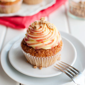 Rhubarb and Custard Cupcakes - These delicious cupcakes are filled with rhubarb puree and topped with a swirl of custard buttercream, rhubarb syrup, and crunchy crumb topping. Yum! | thetoughcookie.com